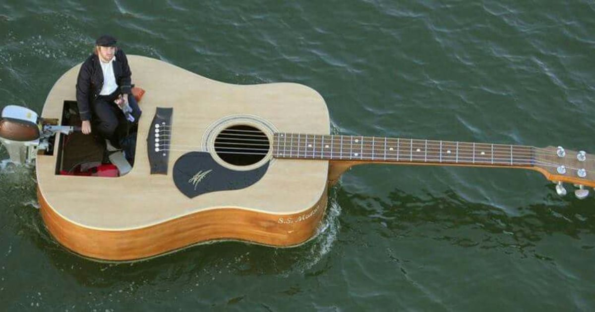 A man in a suit humorously sits atop a guitar floating in water, embodying the essence of guitar-puns.